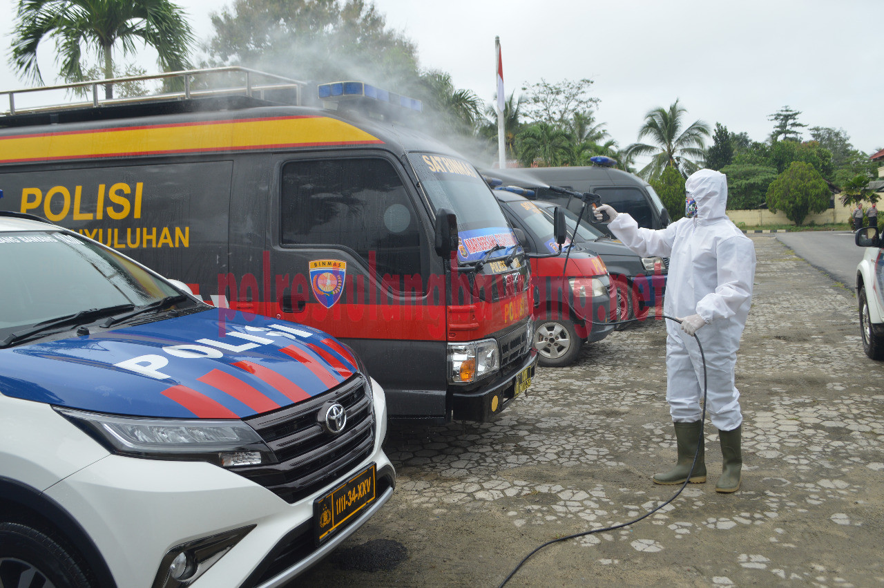 Petugas sedang menyemprotkan cairan desinfektan pada mobil dinas