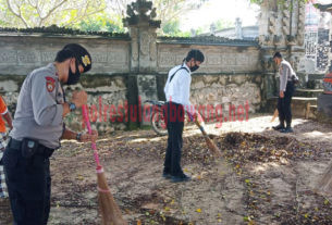 Personel Polres Tulang Bawang sedang membersihkan Pura Desa dan Pura Puseh, Dusun Cakat Raya, Kampung Menggala